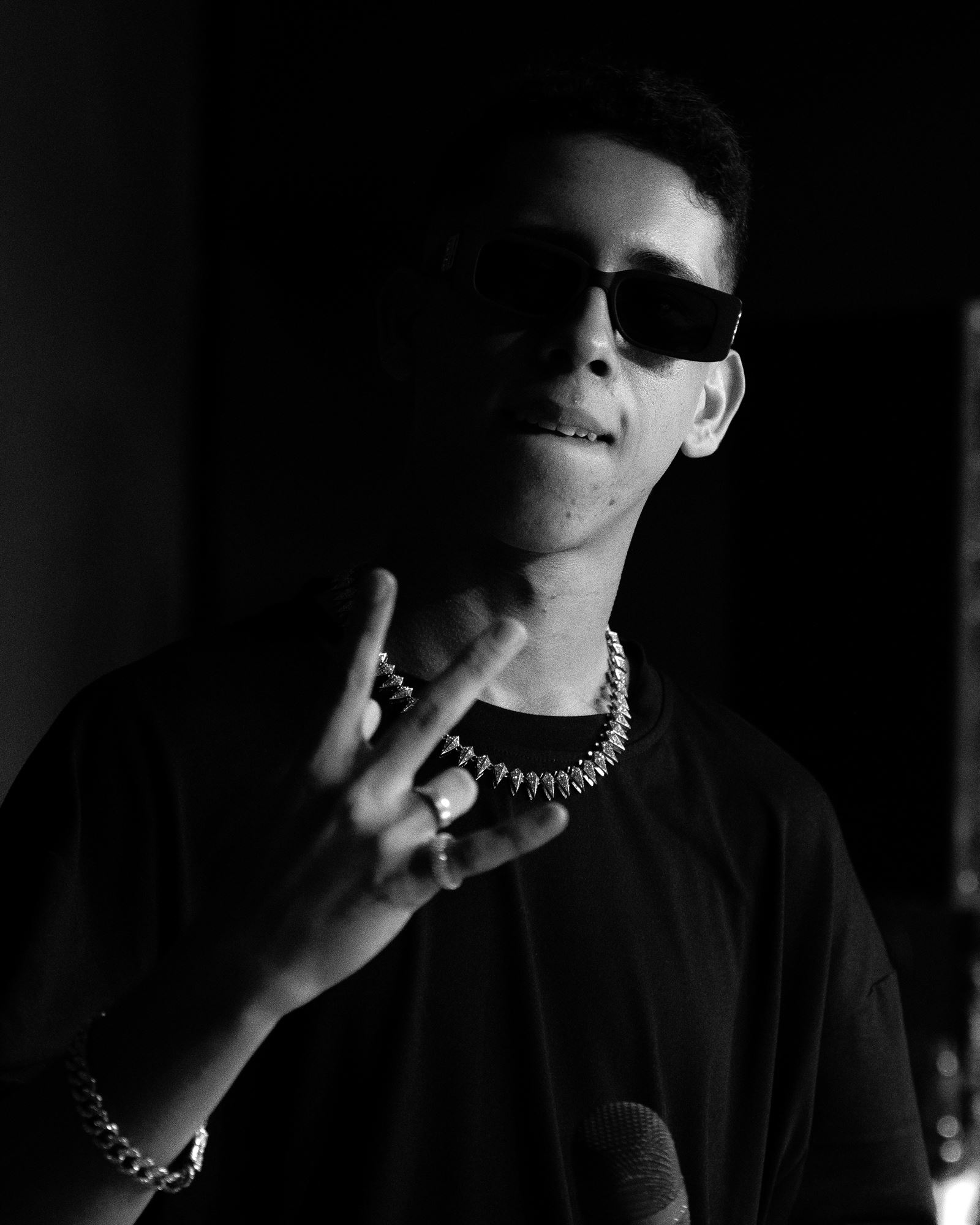 Retrato de Sixxx de óculos escuros fazendo sinal de paz, em preto e branco